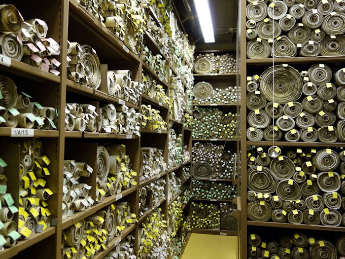 Shelves containing stacked scrolls of parchment featuring British laws