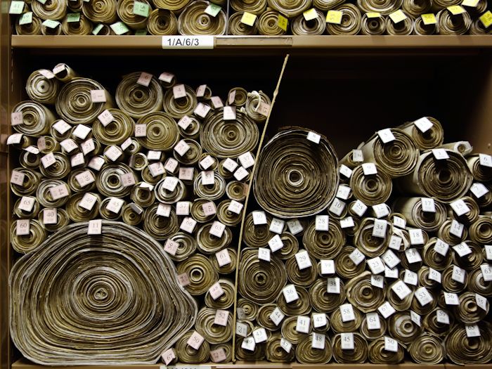 Shelves containing stacked scrolls of parchment featuring British laws