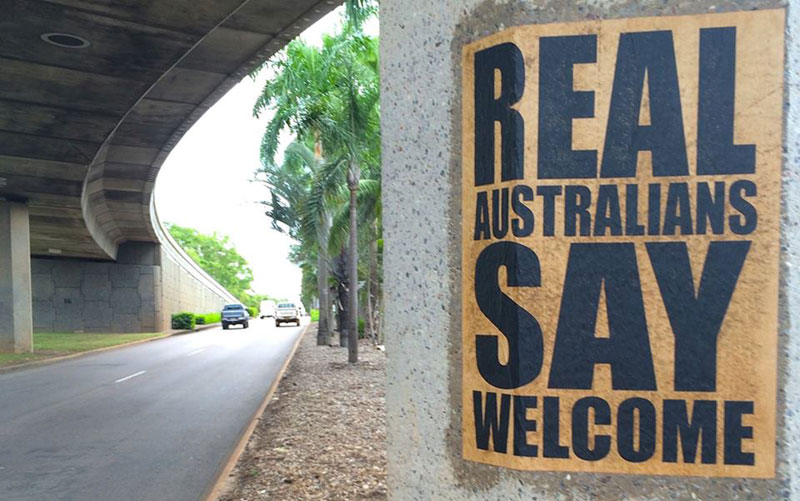 A 'Real Aussies Say Welcome' poster pasted on a bridge pylon