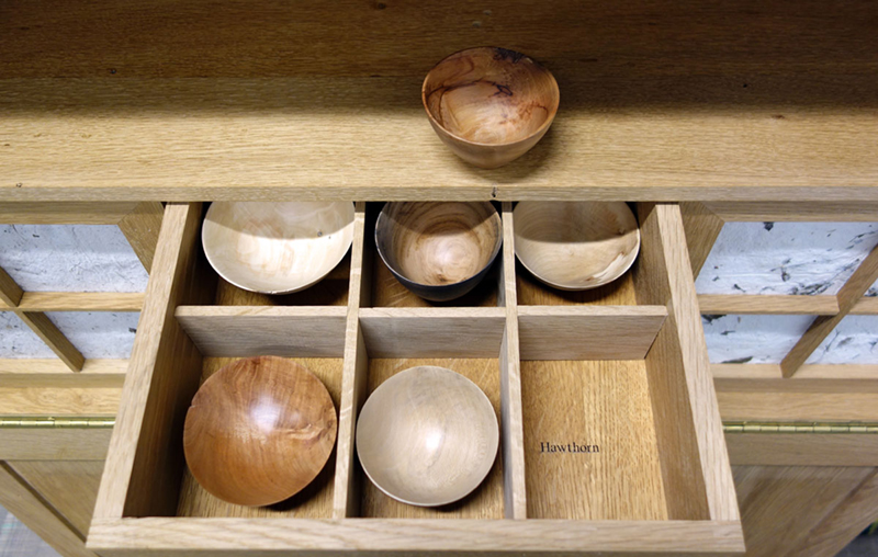 An open draw full of small wooden bowls