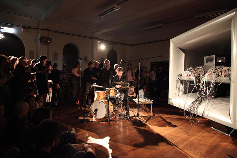 A drummer playing in front of the cellF machine trumpet structure