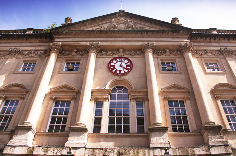 An elegant old building with large columns and windows and a central clock