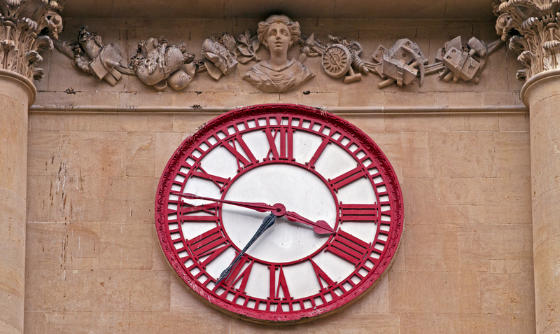 A clockface on the building with red hour and minute hands and an additional black minute hand