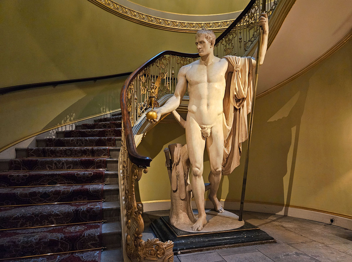 A marble statue at the base of a winding staircase