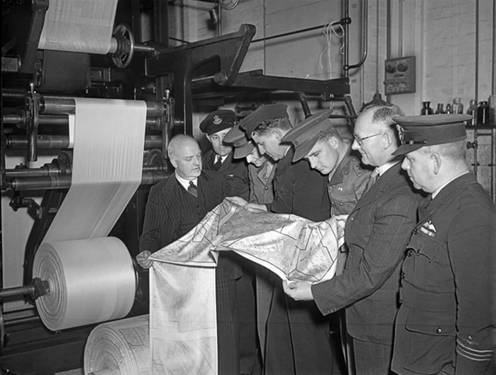 A group of men inspecting a piece of silk printed on a newspaper press