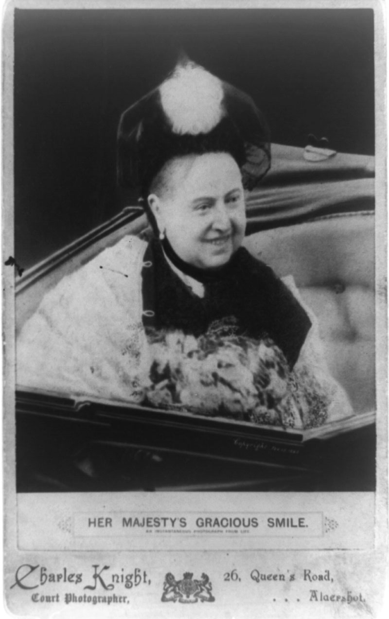 A black and white cabinet card showing Queen Victoria riding in a carriage, smiling