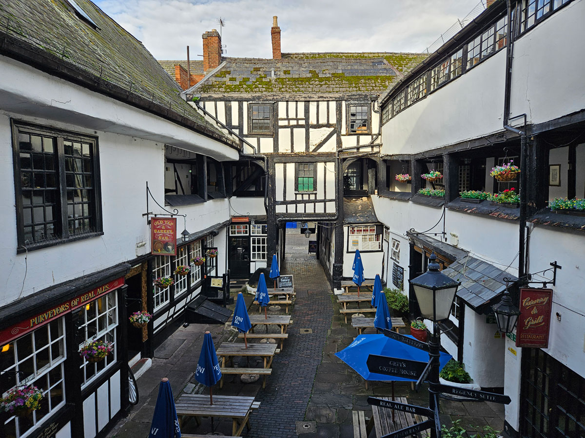 View from the gallery of a Tudor-style coaching inn, looking down onto the courtyard
