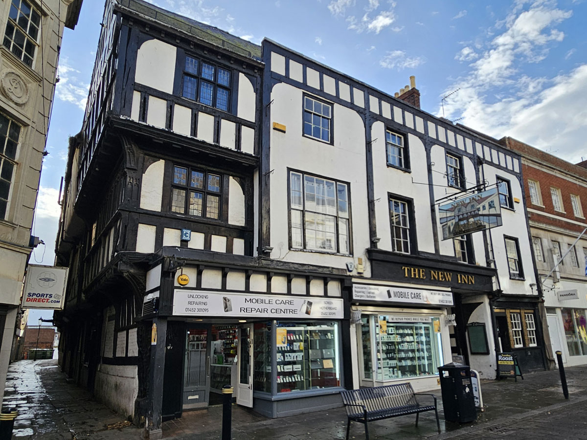 A three storey Tudor-style building on a high street with mobile phone shops on the ground floor.