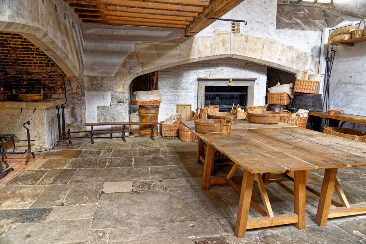 A Tudor-era kitchen with two large wooden tables in the centre of the room