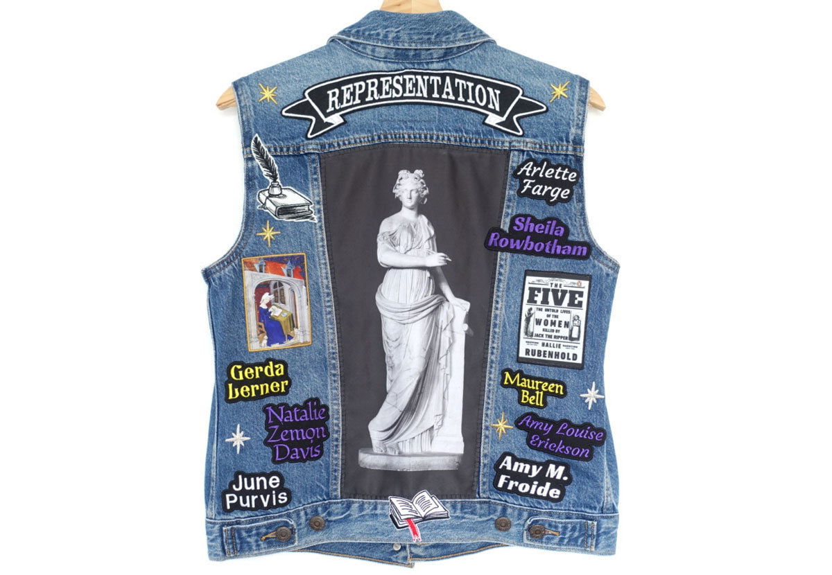 A sleeveless denim jacket decorated with embroidered patches.